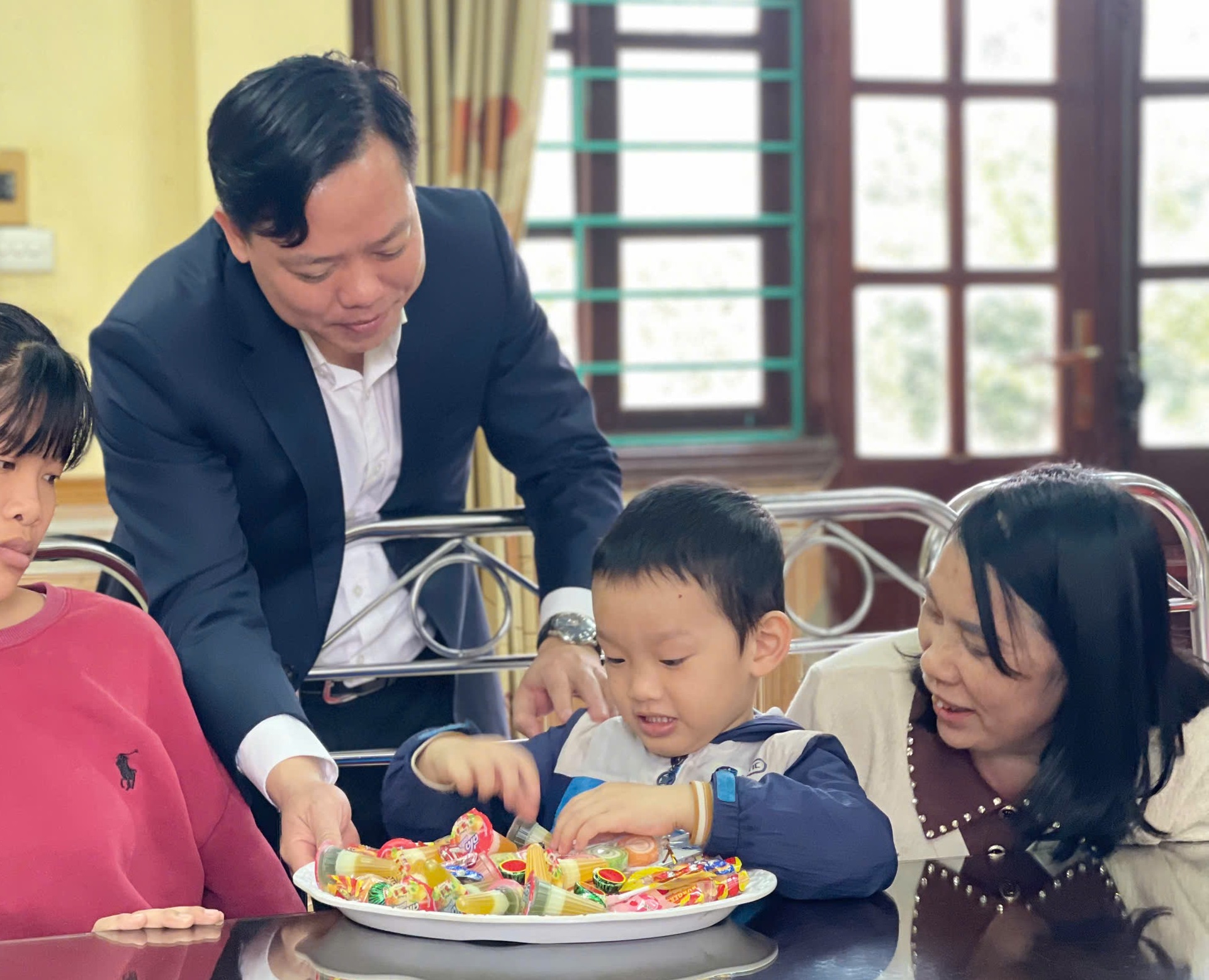 Đồng chí Trần Văn Hùng - Phó Giám đốc Sở LĐTBXH chia bánh kẹo cho trẻ em Làng trẻ em SOS.
